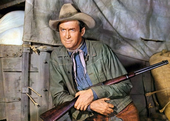 Acteur James Stewart met geweer poseert voor westernfim