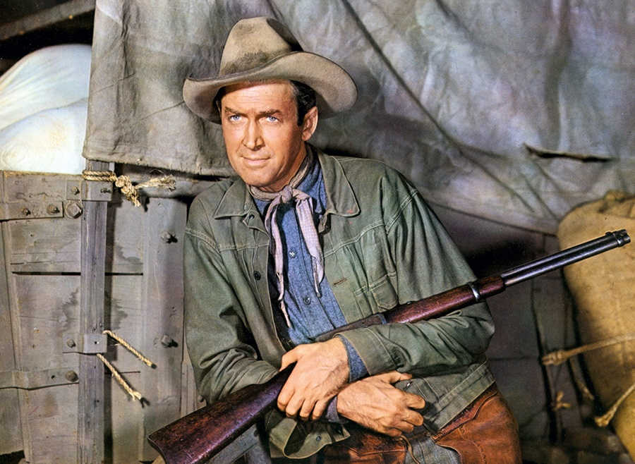 Acteur James Stewart met geweer poseert voor westernfim