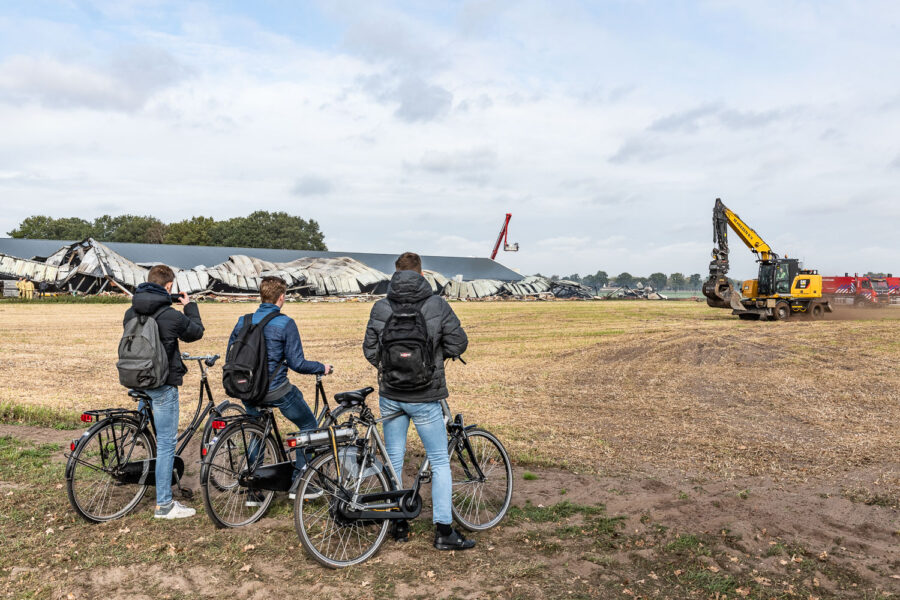 Jongeren kijken naar restanten van afgebrande varkensstal Heusden 2018