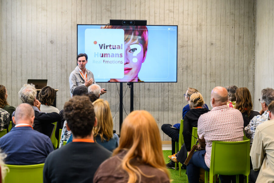 Faces of the Future evenement van Mindlabs Tilburg: Man staat voor scherm met de tekst Virtual Humans Real Emotions